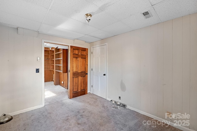 carpeted empty room featuring a drop ceiling