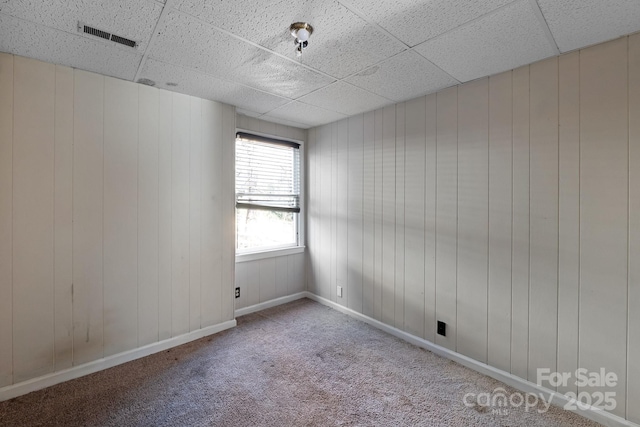 empty room featuring carpet flooring and a drop ceiling