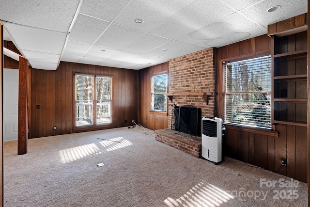 unfurnished living room with a fireplace and wood walls