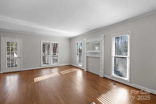 unfurnished living room with ornamental molding, hardwood / wood-style floors, and a wealth of natural light