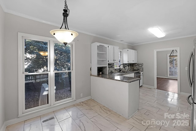 kitchen with tasteful backsplash, white cabinets, dark stone counters, hanging light fixtures, and kitchen peninsula