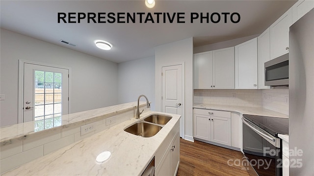 kitchen featuring sink, light stone counters, appliances with stainless steel finishes, dark hardwood / wood-style floors, and white cabinets