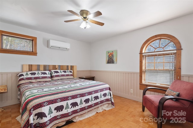 bedroom featuring ceiling fan, light parquet flooring, and a wall mounted AC