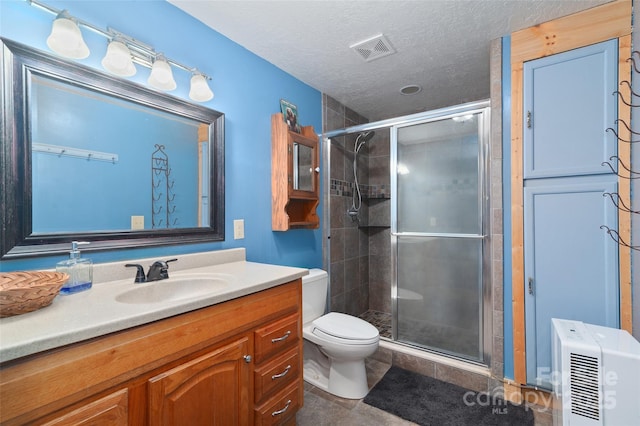 bathroom featuring a shower with door, vanity, a textured ceiling, tile patterned floors, and toilet