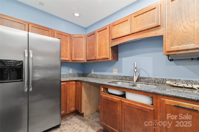 kitchen featuring sink, dark stone counters, and stainless steel refrigerator with ice dispenser