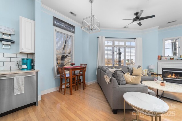 living room featuring crown molding, ceiling fan, plenty of natural light, and light hardwood / wood-style floors