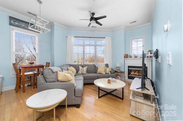 living room with crown molding, a wealth of natural light, and light wood-type flooring
