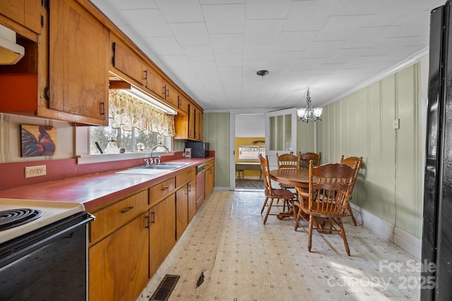 kitchen with black refrigerator, pendant lighting, sink, a chandelier, and stainless steel dishwasher