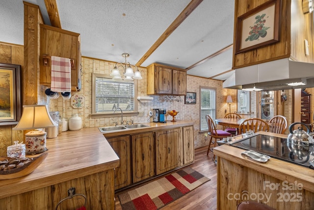 kitchen featuring sink, hanging light fixtures, extractor fan, lofted ceiling with beams, and a textured ceiling