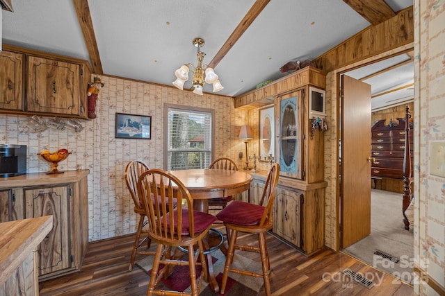 dining space featuring an inviting chandelier, vaulted ceiling with beams, and dark hardwood / wood-style flooring