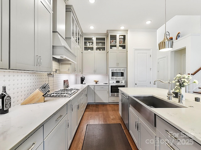 kitchen with premium range hood, appliances with stainless steel finishes, decorative light fixtures, dark hardwood / wood-style flooring, and light stone counters