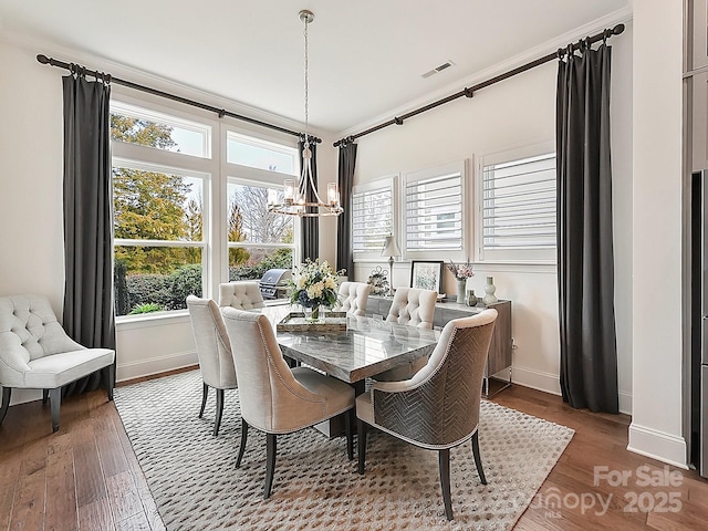 dining room featuring crown molding, dark hardwood / wood-style floors, and an inviting chandelier