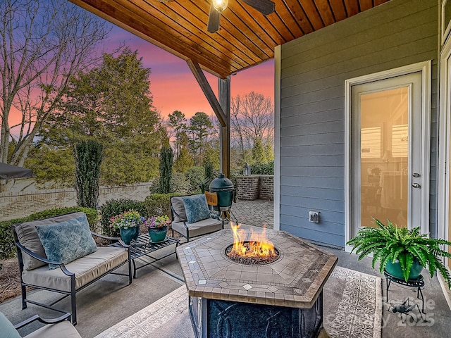 patio terrace at dusk with an outdoor living space with a fire pit and ceiling fan