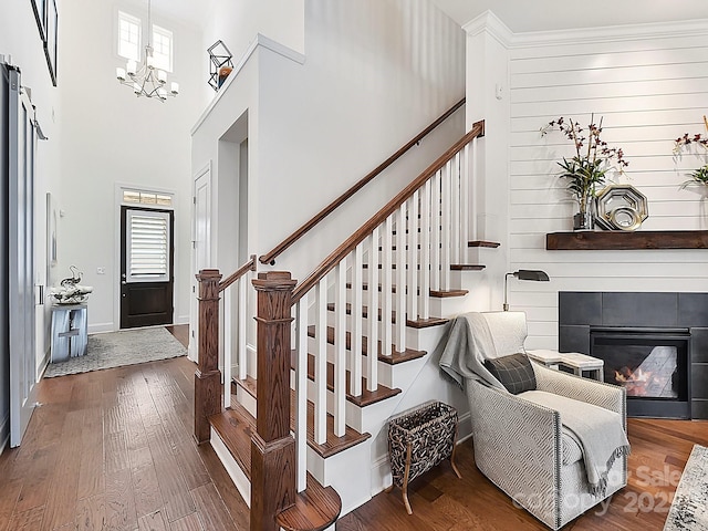 stairs with hardwood / wood-style flooring, a fireplace, a chandelier, and a high ceiling