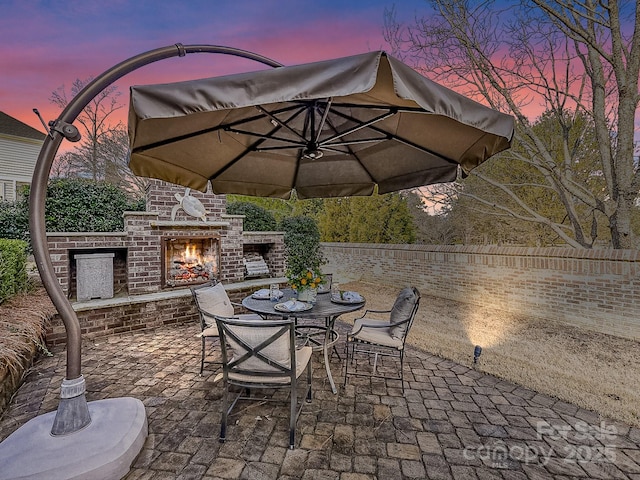 patio terrace at dusk featuring an outdoor brick fireplace