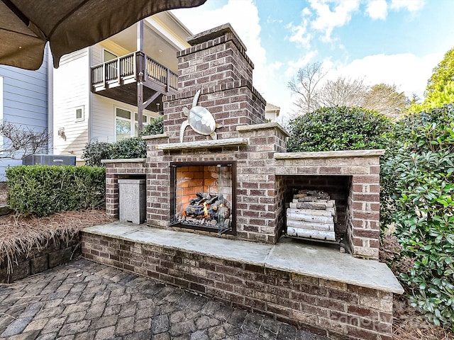 view of patio / terrace featuring an outdoor brick fireplace and a balcony