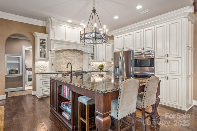 kitchen featuring white cabinetry, stainless steel appliances, decorative light fixtures, and dark stone counters