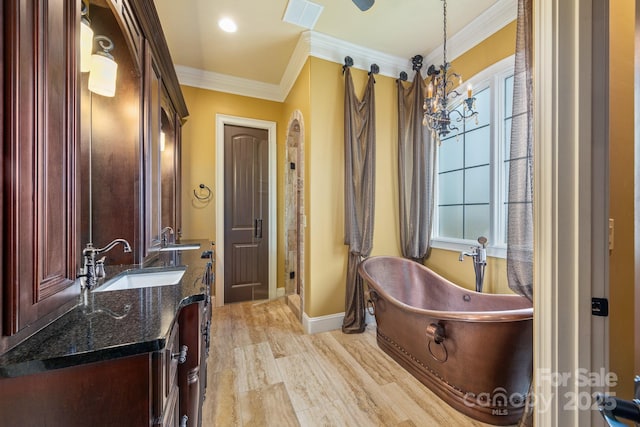 bathroom with a tub to relax in, hardwood / wood-style flooring, vanity, a notable chandelier, and crown molding