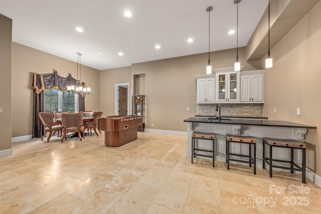 kitchen featuring a breakfast bar area, decorative light fixtures, a chandelier, white cabinets, and backsplash