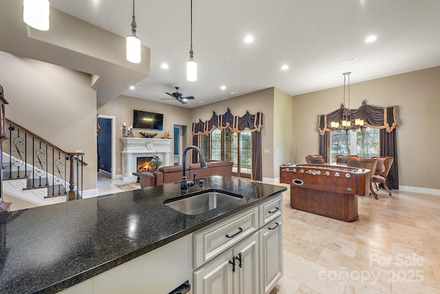 kitchen featuring sink, decorative light fixtures, dark stone counters, and white cabinets