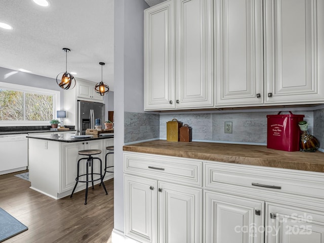 kitchen featuring pendant lighting, dishwasher, stainless steel refrigerator with ice dispenser, white cabinets, and dark hardwood / wood-style flooring