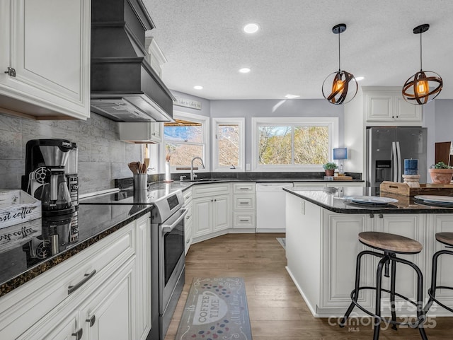 kitchen with white cabinetry, hanging light fixtures, stainless steel appliances, and a kitchen breakfast bar