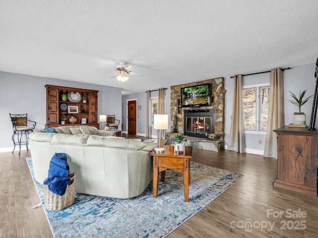 living room featuring hardwood / wood-style flooring, ceiling fan, a textured ceiling, and a fireplace