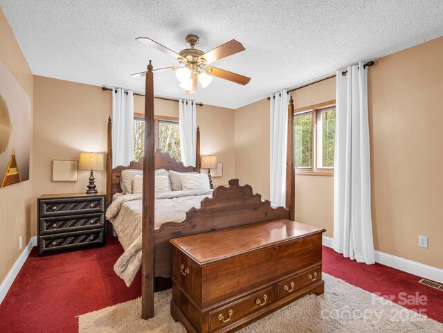 bedroom featuring ceiling fan, dark carpet, and a textured ceiling