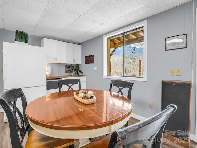 dining space featuring wood-type flooring and a drop ceiling