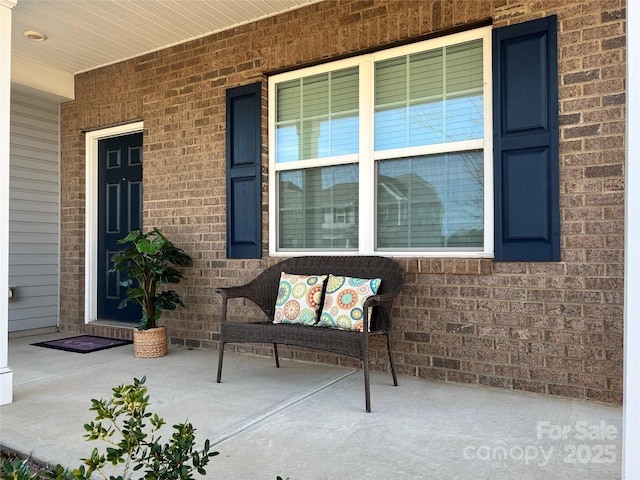 doorway to property with covered porch and brick siding