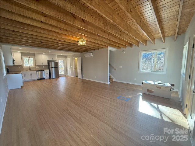 unfurnished living room with sink, wood ceiling, light hardwood / wood-style flooring, a wall unit AC, and beamed ceiling