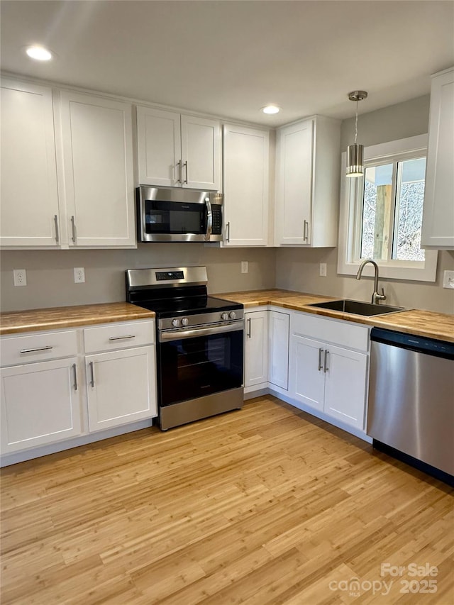 kitchen featuring white cabinetry, wooden counters, and appliances with stainless steel finishes