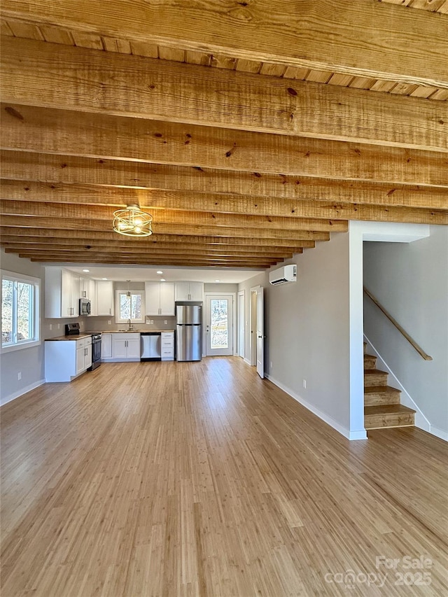 unfurnished living room with beamed ceiling, sink, hardwood / wood-style floors, and a wall unit AC