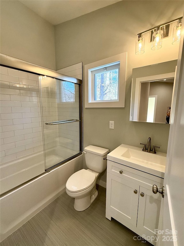 full bathroom featuring vanity, shower / bath combination with glass door, and toilet