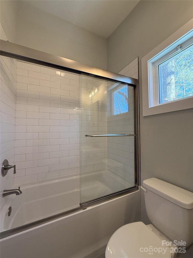 bathroom with combined bath / shower with glass door and toilet