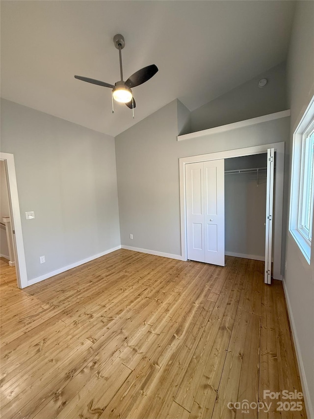 unfurnished bedroom featuring ceiling fan, lofted ceiling, a closet, and light wood-type flooring