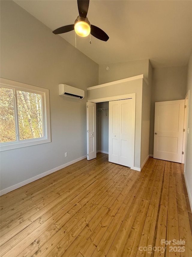 unfurnished bedroom featuring light hardwood / wood-style flooring, ceiling fan, an AC wall unit, vaulted ceiling, and a closet