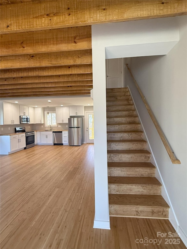 stairs featuring sink and hardwood / wood-style floors