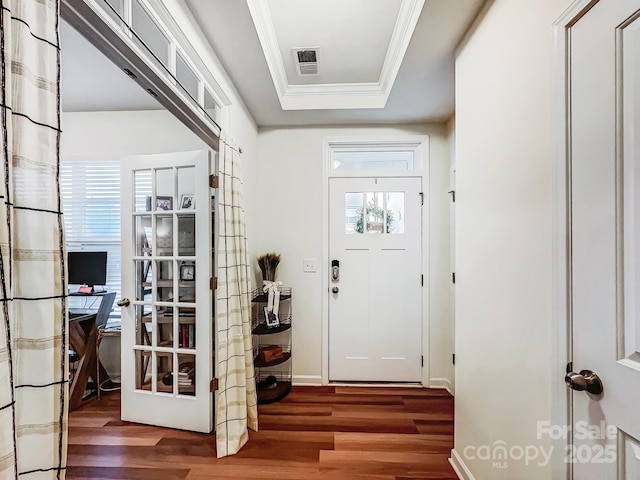 entryway with hardwood / wood-style floors, plenty of natural light, ornamental molding, and a raised ceiling