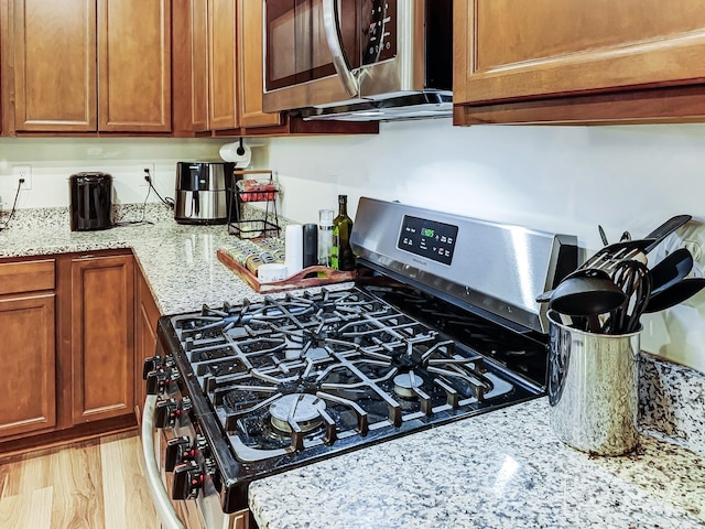 kitchen featuring light stone countertops, light hardwood / wood-style flooring, and stainless steel appliances