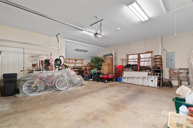 garage featuring a garage door opener, electric panel, and a workshop area