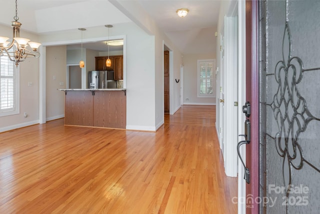 foyer featuring a healthy amount of sunlight, a chandelier, and light hardwood / wood-style flooring