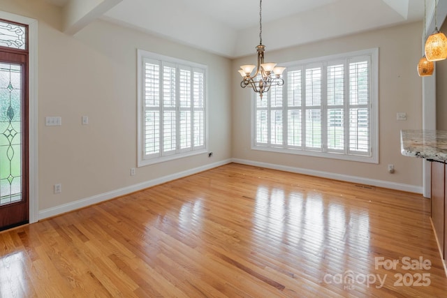 unfurnished dining area with a wealth of natural light, a chandelier, and light wood-type flooring