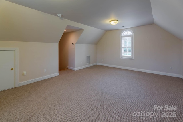 bonus room with vaulted ceiling and light colored carpet