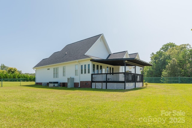 rear view of house featuring central AC unit, a deck, and a lawn