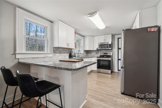 kitchen with white cabinetry, stainless steel appliances, and kitchen peninsula