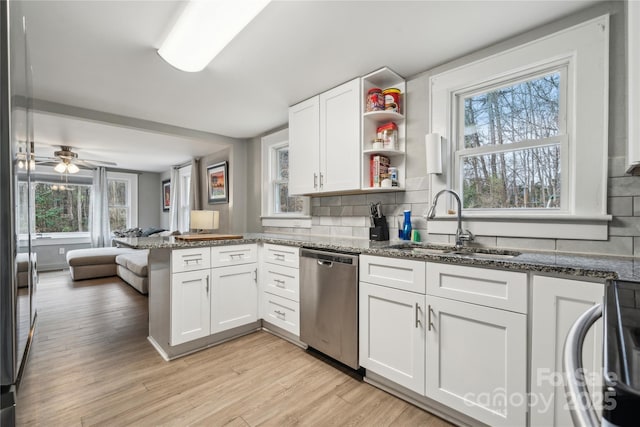 kitchen featuring dishwasher, sink, white cabinets, dark stone counters, and kitchen peninsula