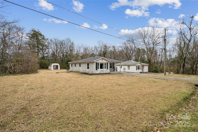 ranch-style house with a shed, a front yard, and covered porch