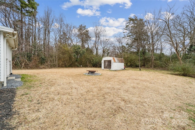 view of yard featuring a fire pit and a storage unit