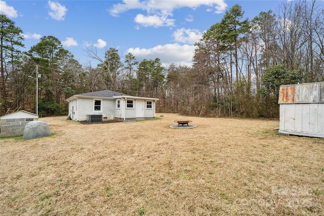 view of yard featuring an outdoor structure, central air condition unit, and a fire pit